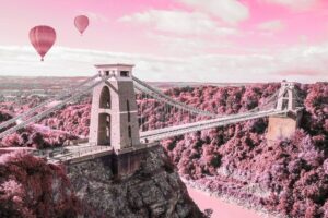 pink and grey arty photo style graphic of Clifton Suspension Bridge in Bristol with two hot air balloons
