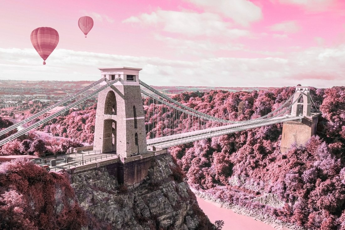 pink and grey arty photo style graphic of Clifton Suspension Bridge in Bristol with two hot air balloons