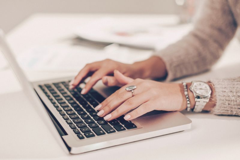 woman with watch typing on a laptop