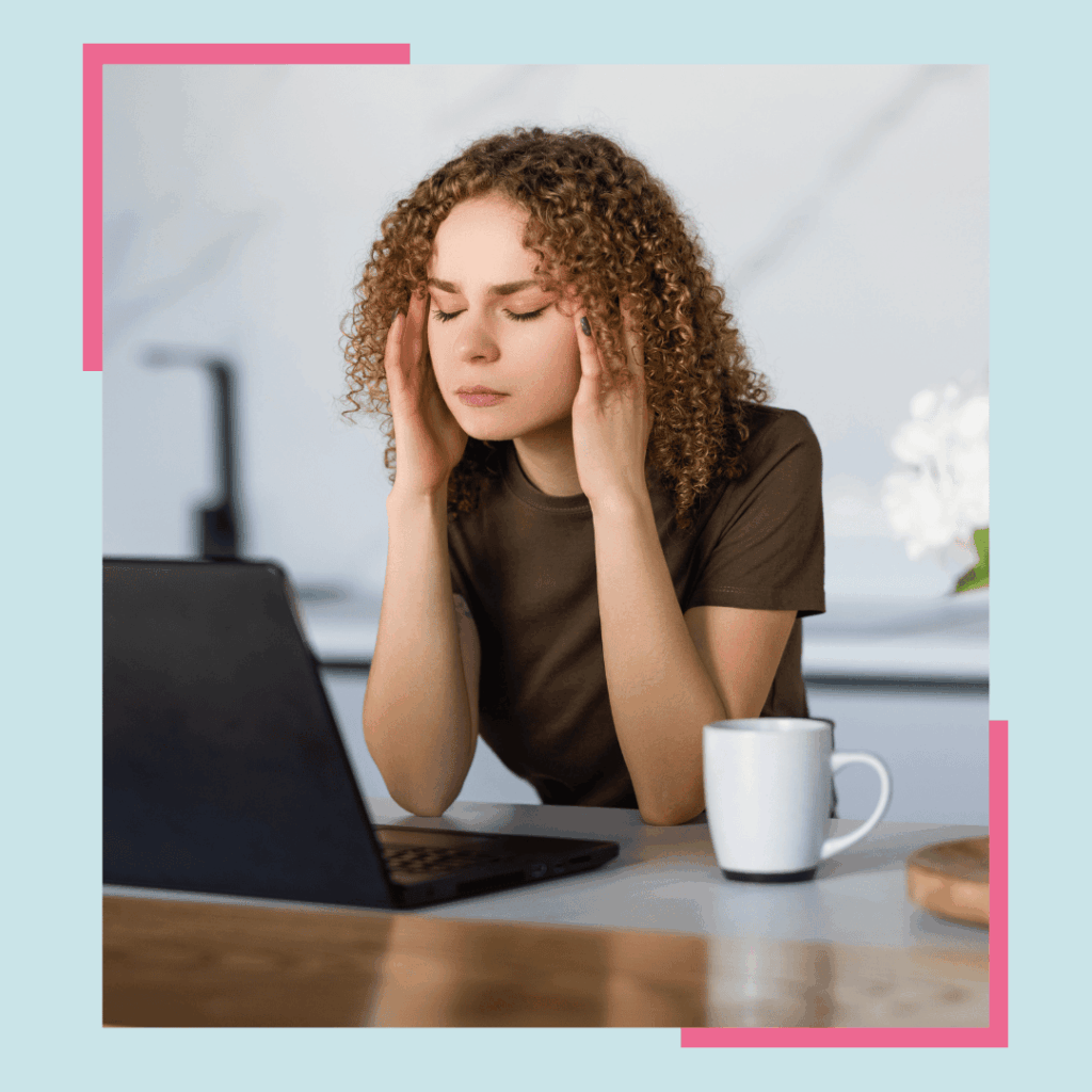 frustrated woman working on laptop with a cup of coffee next to her